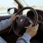 Close-up of hands on steering wheel while driving through Mexico in daylight.